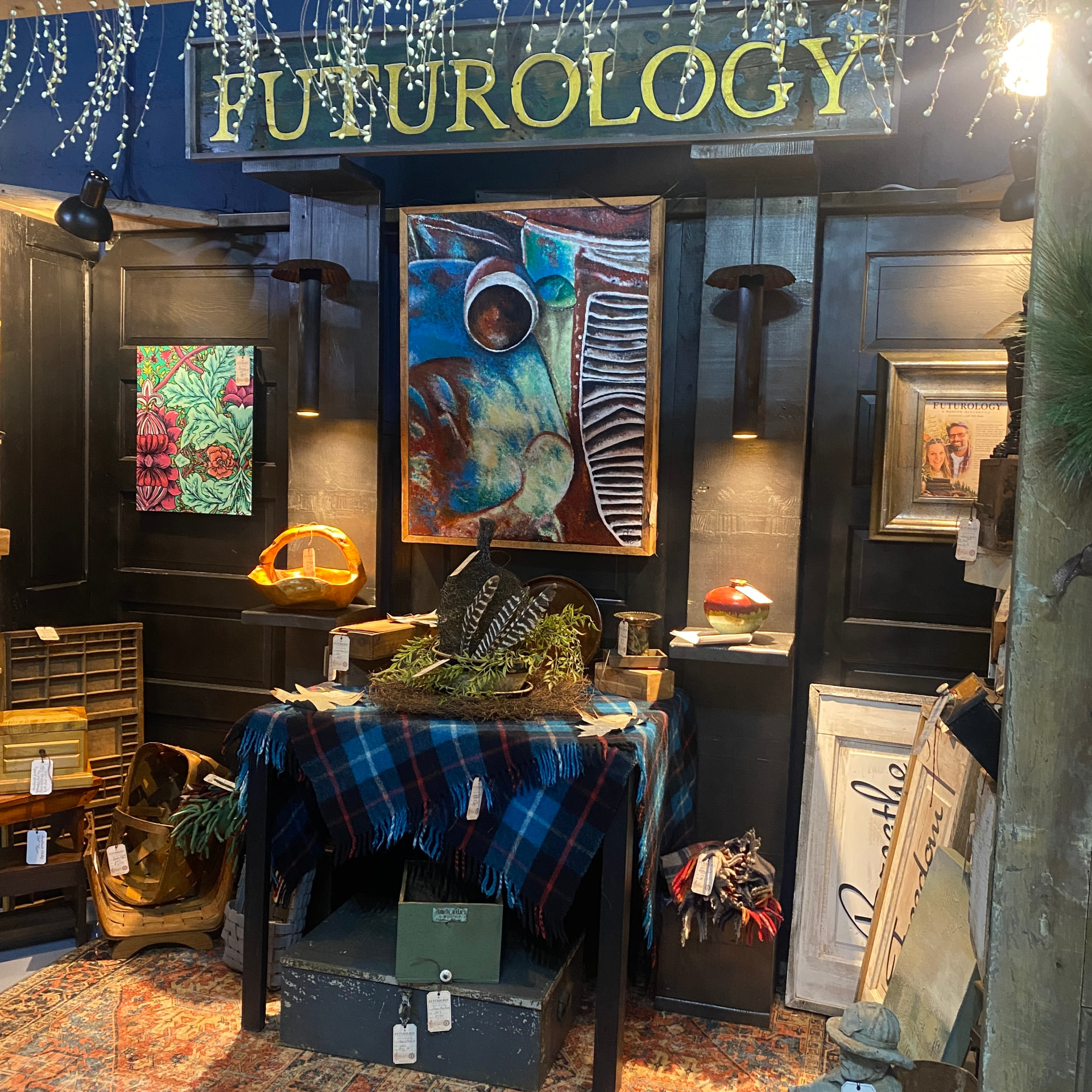 The FUTUROLOGY sign glowing above art, pottery and a plaid wool throw
