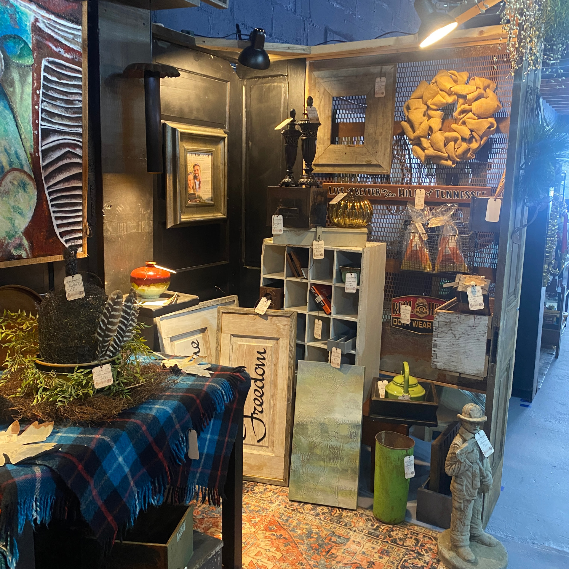 A booth corner with vintage signage, stoneware and a carved folk figure